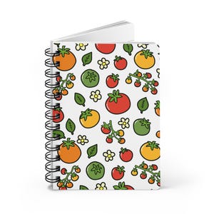 May include: A spiral-bound notebook featuring a repeating pattern of red, orange, and green tomatoes, small green leaves, and white flowers on a light gray background. The notebook has a black metal coil spine along the left side.