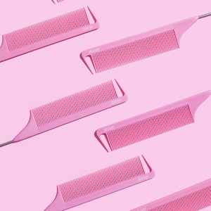 May include: Five pink combs with long, thin, silver handles. The combs have a pointed end and a row of teeth. The combs are arranged in a diagonal pattern on a pink background.