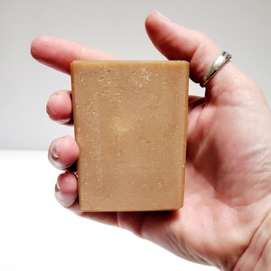 May include: A rectangular bar of brown soap with a slightly grainy texture.