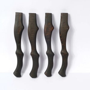 Può includere: Quattro gambe in legno marrone scuro con un design curvo unico. Le gambe sono in legno e hanno una finitura marrone scuro.