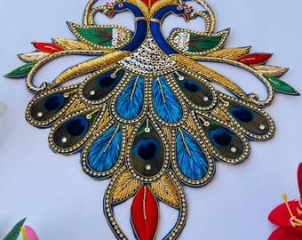 May include: A blue and gold embroidered peacock design with red accents. The peacock has a detailed tail with blue, green, and gold feathers.