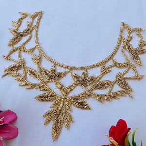 Peut inclure: Broderie en perles dorées avec un motif de feuilles. La broderie est en forme de décolleté et serait parfaite pour embellir des vêtements ou des accessoires.