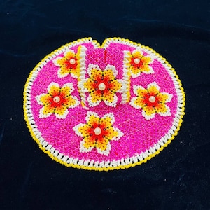 Pode incluir: Um conjunto de bebê de contas rosa com flores amarelas e brancas. O conjunto é decorado com pequenas contas brancas e tem uma forma redonda.