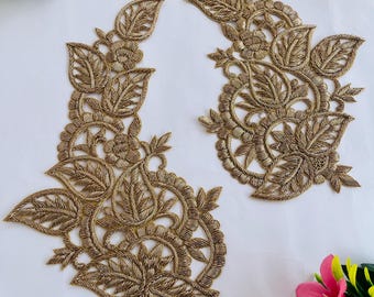 May include: Two gold-colored, embroidered floral appliques with intricate leaf and flower designs. The appliques are placed on a white background, with colorful flowers in the corners. The appliques are likely for embellishing clothing or crafts.