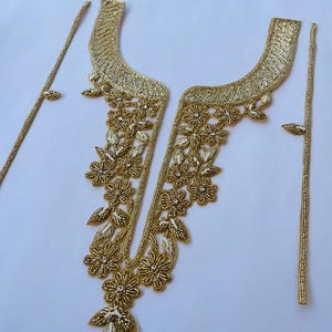 Op de afbeelding: Gouden kralenborduursel met bloemenmotieven. De versiering is in drie delen, twee lange stroken en een groter deel met een V-vormige halslijn.