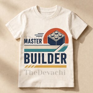 Op de afbeelding: Een crèmekleurig t-shirt met korte mouwen en een grafische print met de tekst MASTER BUILDER. Het ontwerp bevat een donkerblauw bouwblok, een rode halve cirkel en horizontale strepen in blauwgroen en geel, met de tekst TheDevachi zichtbaar.