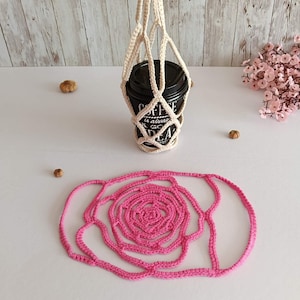 May include: A cream-colored, crocheted coffee cup holder with a black cup inside, and a pink crocheted coaster in the shape of a rose. The cup reads "Coffee is always a good idea."
