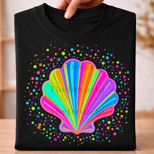 May include: A black t-shirt featuring a large, vibrant, multi-colored seashell graphic in the center. The shell is composed of radiating stripes in shades of pink, orange, yellow, green, and blue, surrounded by a circular pattern of colorful dots.