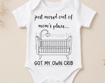 May include: White baby onesie with the text "just moved out of mom's place... GOT MY OWN CRIB" and a black and white illustration of a crib. The onesie has short sleeves and a round neckline.