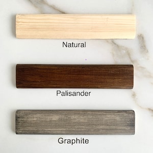 May include: Three wood samples showing different color options: Natural, Palisander, and Graphite.