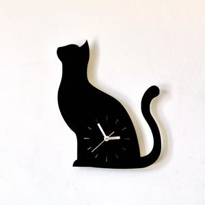 Peut inclure: Horloge murale en forme de silhouette de chat noir avec des aiguilles blanches.