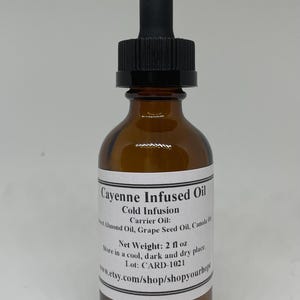 May include: A brown glass bottle with a black dropper top. The bottle is labeled "Cayenne Infused Oil" and contains 2 fluid ounces of oil. The label also includes the text "Cold Infusion", "Carrier Oil: Sweet Almond Oil, Grape Seed Oil, Canola Oil", "Store in a cool, dark and dry place", "Lot: CARD-1021", and "www.etsy.com/shop/shopvourhope".