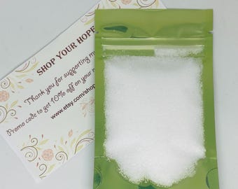 May include: A small green resealable bag filled with white bath salts. The bag is labeled with the text "SHOP YOUR HOPE" and a discount code.