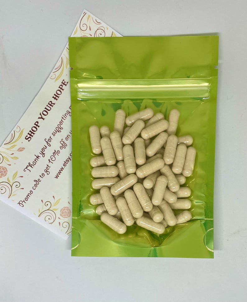 May include: A clear, lime green, resealable bag filled with beige capsules. A white card with the text "SHOP YOUR HOPE" and other text is visible behind the bag. The capsules are cylindrical and appear to be supplements.