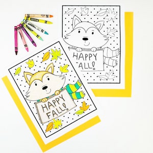 May include: Two coloring pages featuring a cartoon fox holding a sign that says "Happy Fall!" The fox is wearing a scarf and surrounded by leaves. Crayons in various colors are arranged near the pages. The pages are on a white background with yellow borders.