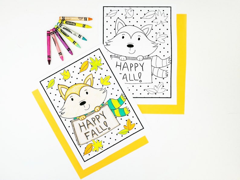 May include: Two coloring pages featuring a cartoon fox holding a sign that says "Happy Fall!" The fox is wearing a scarf and surrounded by leaves. Crayons in various colors are arranged near the pages. The pages are on a white background with yellow borders.