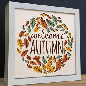 May include: White framed canvas wall art with a circle of colorful autumn leaves and the text "welcome autumn".