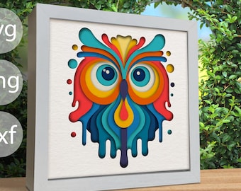 May include: A colorful paper cut-out design of an owl with dripping paint effects in shades of red, orange, yellow, blue, and green. The owl's eyes are large and blue with yellow pupils.