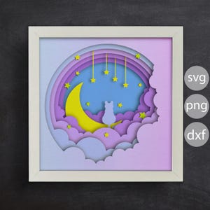 Könnte beinhalten: Eine weiße Silhouette einer Katze, die auf einem gelben Halbmond sitzt, umgeben von lila und blauen Wolken und Sternen. Das Bild befindet sich in einem weißen Rahmen vor schwarzem Hintergrund.