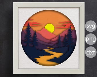 Può includere: Un design di taglio di carta che rappresenta un tramonto su una catena montuosa con un fiume che serpeggia attraverso la valle. Le montagne sono stratificate in tonalità di viola, rosa e rosso, con un sole giallo nel cielo. Il fiume è di un colore arancione brillante, e gli alberi sono blu scuro.