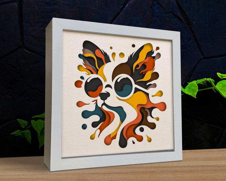 May include: A white framed picture with a colorful paper cut-out design of a dog wearing sunglasses. The dog is surrounded by colorful abstract shapes.