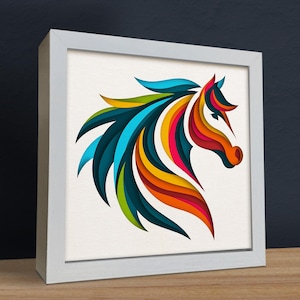 May include: A colorful paper cut-out of a horse's head in a white frame. The horse's mane and body are made of layered paper in shades of blue, green, yellow, orange, and red.