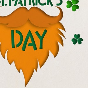 May include: Orange paper cut-out of a beard with the word "DAY" in green letters inside. There are three green shamrocks on the right side of the image.