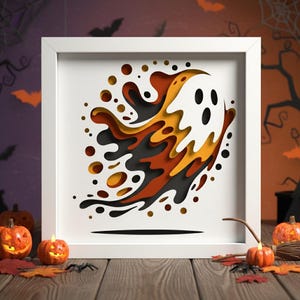 Könnte beinhalten: Ein gerahmtes Halloween-Kunstwerk mit einem mehrschichtigen Geisterdesign in Weiß, Schwarz, Orange und Gelb. Das Kunstwerk ist vor einem Hintergrund mit Kürbissen, Blättern und einer Spinne platziert, was eine festliche Atmosphäre schafft.