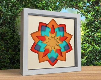 May include: A framed paper art piece with a colorful, layered, geometric flower design in shades of orange, red, blue, and yellow.
