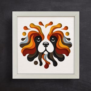 Op de afbeelding: Een ingelijste kunstdruk met een gestileerd hondenportret. Het gezicht van de hond is wit met gelaagde papieren uitsparingen in zwart, bruin, oranje en geel. Het kunstwerk staat tegen een witte achtergrond en is ingelijst in een witte vierkante lijst.