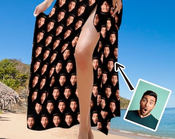 May include: A black beach cover-up featuring a repeating pattern of a man's face with a surprised expression. The fabric is draped to show a high side slit. A small inset image shows the original photograph of the man used for the print.