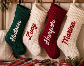 May include: Four cable-knit Christmas stockings hanging from hooks, featuring folded cuffs and embroidered names. The stockings are colored dark green, cream, dark red, and cream, with the names Hudson, Lucy, Harper, and Marina stitched on them.