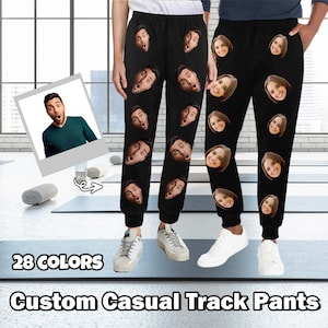 Może przedstawiać: Czarne spodnie dresowe z nadrukiem wielu twarzy. Na dole zdjęcia widnieje tekst "28 COLORS" i "Custom Casual Track Pants".
