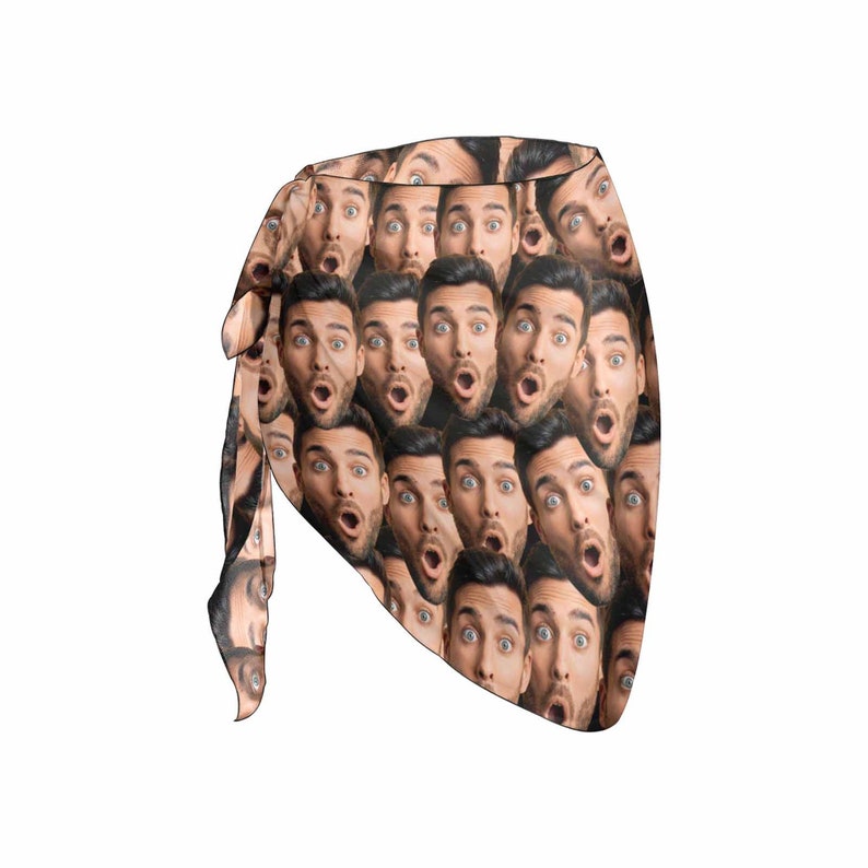 May include: A tan sarong with a repeating pattern of a man's face with a surprised expression.