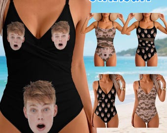 May include: A black one-piece swimsuit featuring a repeating custom face print with a surprised expression. The garment has thin shoulder straps and a V-neckline. The text CUSTOM FACE SWIMSUIT is displayed at the top, with 8+ STYLES and 29+ COLORS.