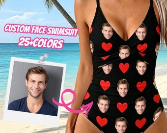 May include: A black one-piece swimsuit featuring a repeating pattern of red hearts and a custom printed face. The swimsuit has thin shoulder straps and a V-neckline. A square photo of the same face is shown on a white card with a pink arrow.