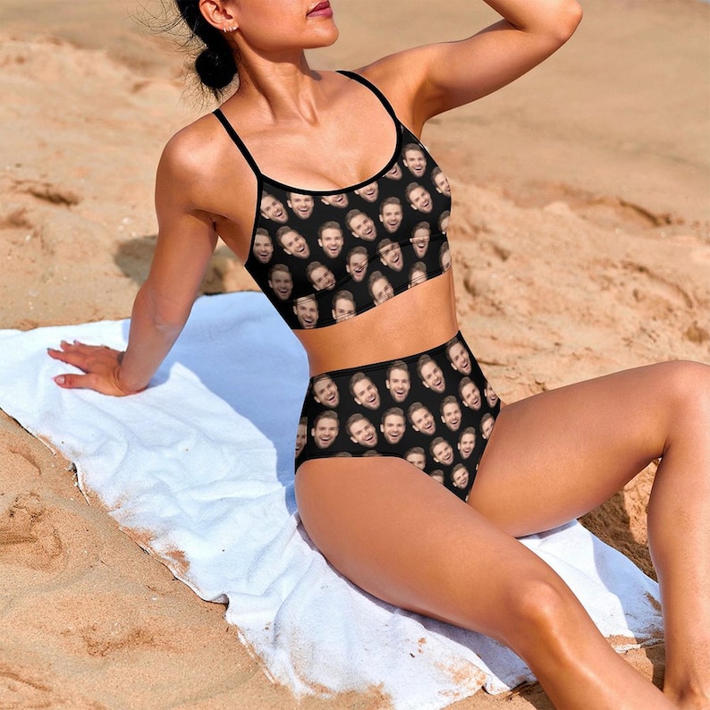 May include: A black swimsuit with a high-waisted bottom and a halter top. The swimsuit is covered in a pattern of a person's face.