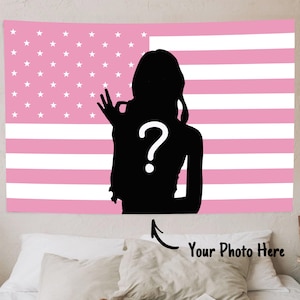 May include: Pink and white American flag tapestry with a black silhouette of a person making an OK gesture. A white question mark is in the center of the silhouette. The text "Your Photo Here" is below the tapestry.