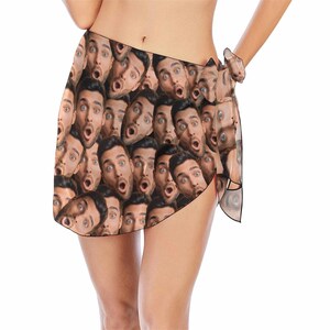 May include: A brown and black sarong with a pattern of repeating faces. The faces are all of the same person with a surprised expression.
