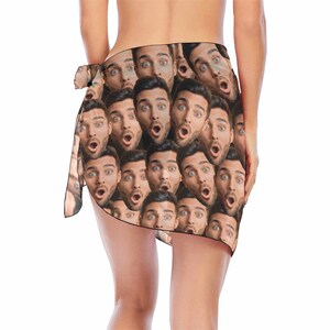 May include: A brown sarong with a repeating pattern of a man's face with a surprised expression.