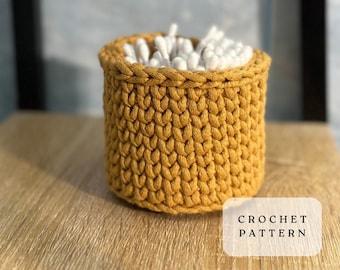 Puede incluir: Un porta hisopos de algodón tejido a crochet de color amarillo mostaza. El porta hisopos está lleno de hisopos de algodón blancos. El texto "CROCHET PATTERN" es visible en la parte inferior de la imagen.