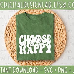 May include: A forest green t-shirt featuring the white text CHOOSE HAPPY with two smiley faces integrated into the letters. The shirt is folded and centered on a round, woven, light brown straw placemat. The design is clear and bold.