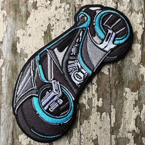 May include: A black and blue embroidered patch of a futuristic motorcycle with a single wheel.