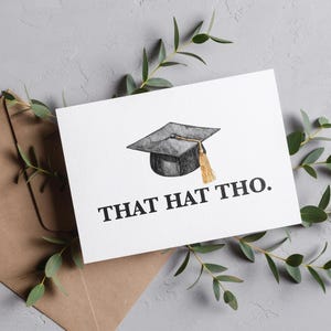 May include: A white card with a black and white illustration of a graduation cap and the text "THAT HAT THO." The card is on a brown envelope with green leaves.