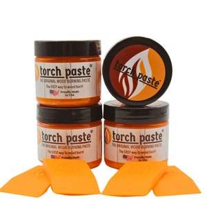 May include: Four orange jars of wood burning paste labeled "torch paste" with the text "The Original Wood Burning Paste" and "The Easy Way to Wood Burn!"  The jars are arranged in a pyramid shape with the top jar centered and the bottom two jars on either side.  The jars have black lids and are made in the USA.