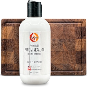 May include: A white bottle of food grade pure mineral oil for cutting boards. The bottle is labeled "torch paste" and says "Protect & Restore". The bottle is 8 fl oz (236 ml) and is made in the USA with ingredients sourced in Canada. The bottle is next to a wooden cutting board.