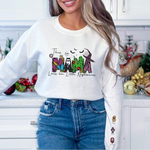 a woman standing in a kitchen wearing a white sweatshirt