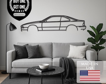May include: Black carbon steel wall art depicting a car silhouette. The artwork is mounted on a white wall above a gray sofa. The image includes a "Buy One Get One" offering and "Made in USA" text.