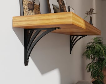 May include: Black metal shelf brackets with a decorative design, supporting a wooden shelf with two framed pictures on top.