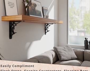 May include: A wooden shelf with black metal brackets, mounted on a white wall. The shelf is decorated with framed artwork and a potted plant. The shelf is in a living room setting with a couch and a window in the background. The text on the artwork reads "FREE WILD AND ALL THINGS ARE GOOD".